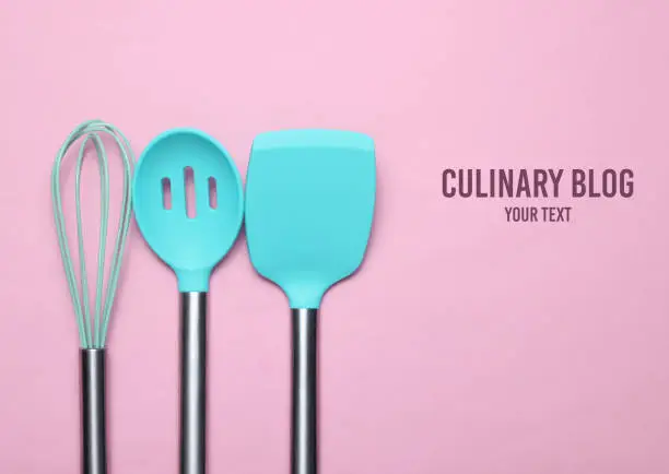 Set of tools for cooking on pink background. Culinary Blog. Silicone paddles with metal handles, whisk. Top view. Copy space.
