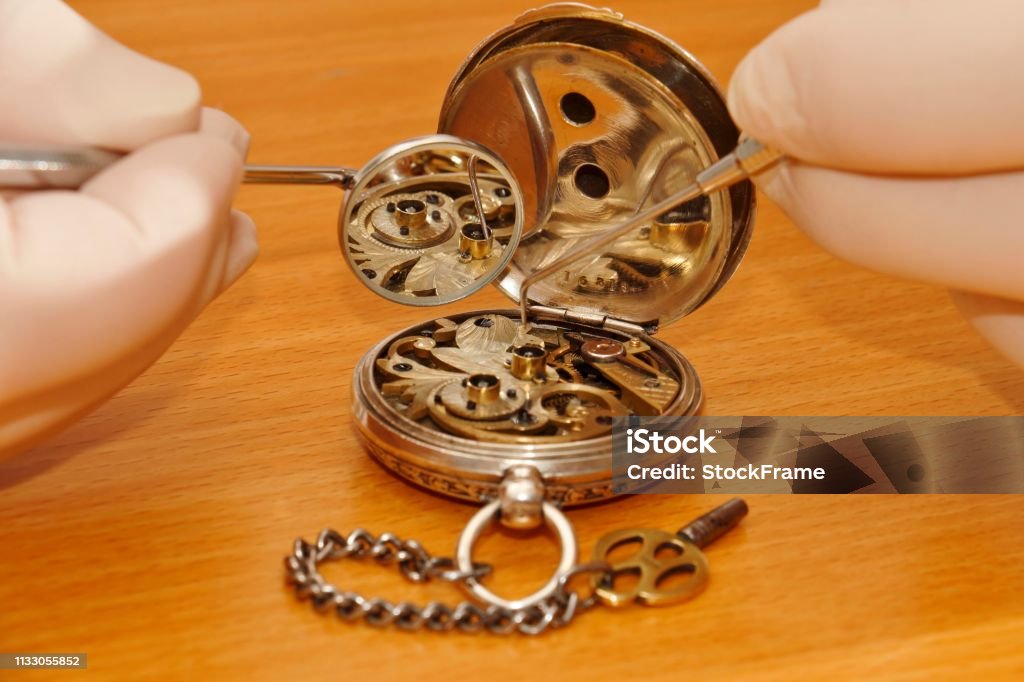 Dentist and watch examination by watchmaker with dentist cutlery, old silver watch, gear wheel Austria Stock Photo
