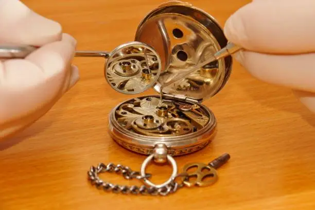 examination by watchmaker with dentist cutlery, old silver watch, gear wheel