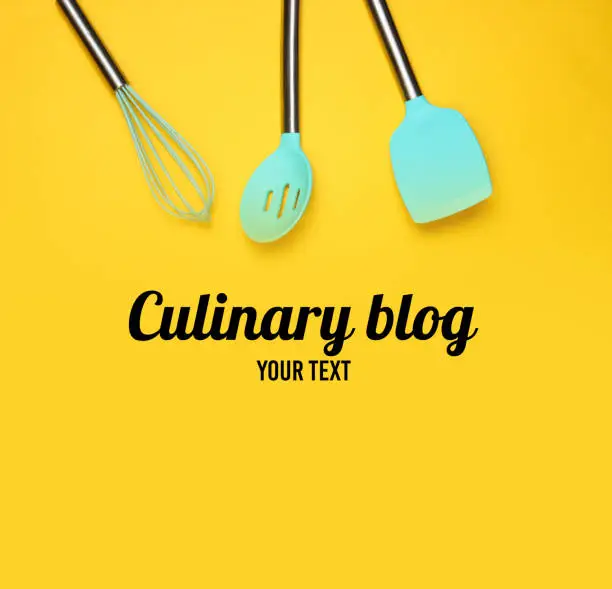 Set of tools for cooking on yellow background. Culinary blog. Silicone paddles with metal handles, whisk. Top view. Copy space.