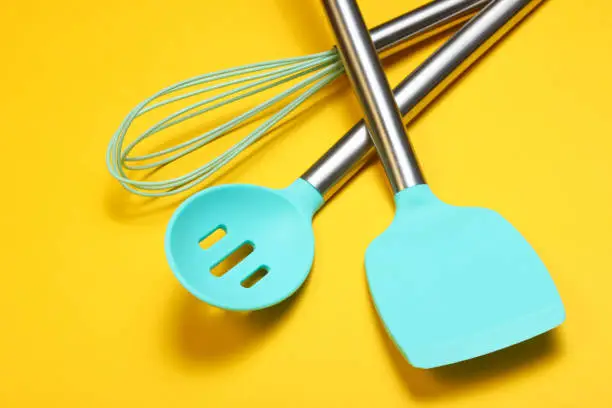 Set of tools for cooking on the background. Silicone paddles with metal handles, whisk.