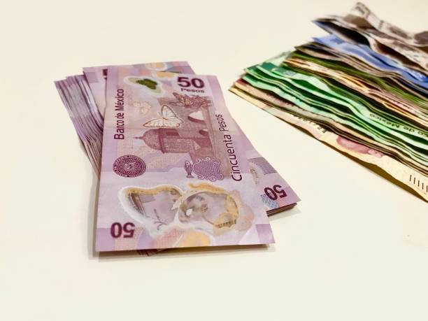 istock Many mixed Mexican peso bills spread over a beige desk 1133058565