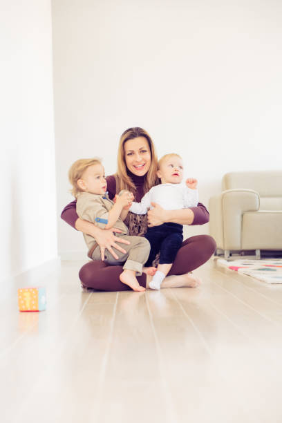 istock Happy mother sitting on the floor with her two babies and playing. 1133063727