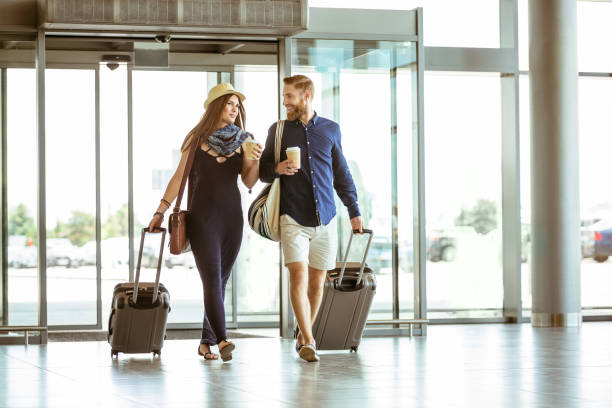istock Couple with luggage talking while entering airport 1133064689