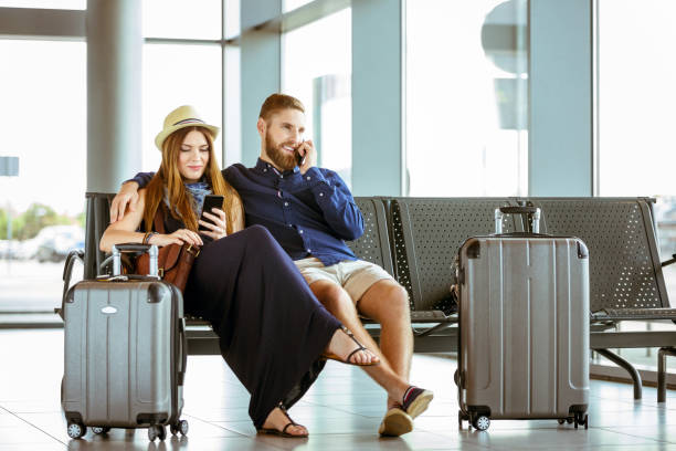 istock Couple using mobile phones while waiting at airport 1133066163