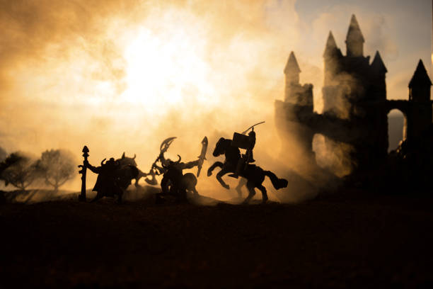 istock Medieval battle scene with cavalry and infantry. Silhouettes of figures as separate objects, fight between warriors on sunset foggy background. 1133071710