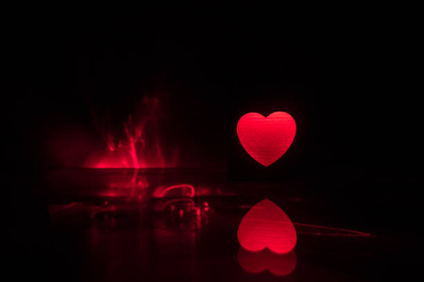 istock Blurred neon heart icon on a dark background. Copy space with red bright colorful heart on black background 1133074145