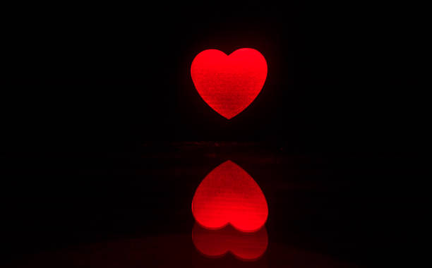 istock Blurred neon heart icon on a dark background. Copy space with red bright colorful heart on black background 1133074146