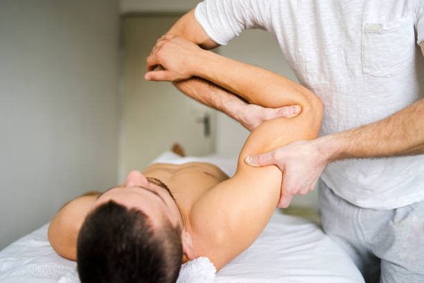 fisioterapeuta masculino dando masaje deportivo al joven hombre en el salón - male towel men human face fotografías e imágenes de stock