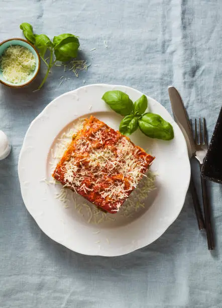 vegan lasagna with lentils and green peas in a baking sheet on a table with a blue linen tablecloth. healthy Italian cuisine for the whole family, party or restaurant