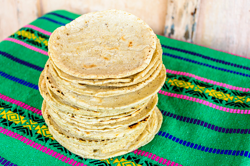 Stack of traditional handmade Guatemalan corn tortillas a staple food in Guatemala on green striped handwoven tablecloth