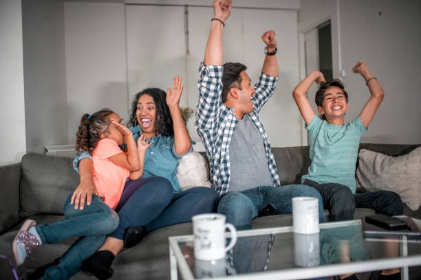 istock Family cheering while watching TV at home 1133081670