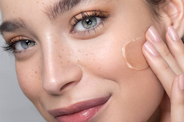 Young woman with perfect skin applying foundation Close up studio shot of a beautiful woman with perfect freckled skin, applying foundation. foundation make up stock pictures, royalty-free photos & images