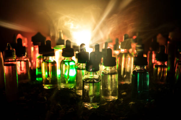 istock Vape concept. Smoke clouds and vape liquid bottles on dark background. Light effects. Useful as background or electronic cigarette advertisement. 1133088193