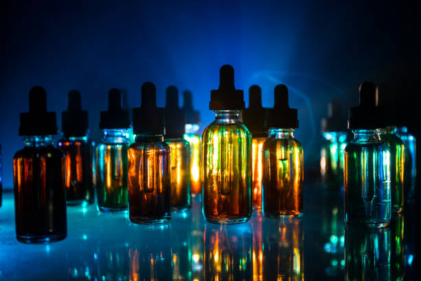 istock Vape concept. Smoke clouds and vape liquid bottles on dark background. Light effects. Useful as background or electronic cigarette advertisement. 1133088200