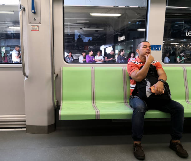 Hispanic adult man sitting in a metro, mass public transport while traveling Hispanic adult man sitting in a metro, mass public transport. Traveling on the train. Interior of the vehicle. Medellin, Colombia. 11/24/2018. metro medellin stock pictures, royalty-free photos & images