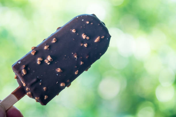 istock Ice cream in chocolate with nuts on stick in hand 1133107105