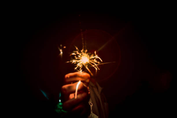 as pessoas estão segurando fogos de artifício em celebrações. - sparkler sparks new years eve human hand - fotografias e filmes do acervo