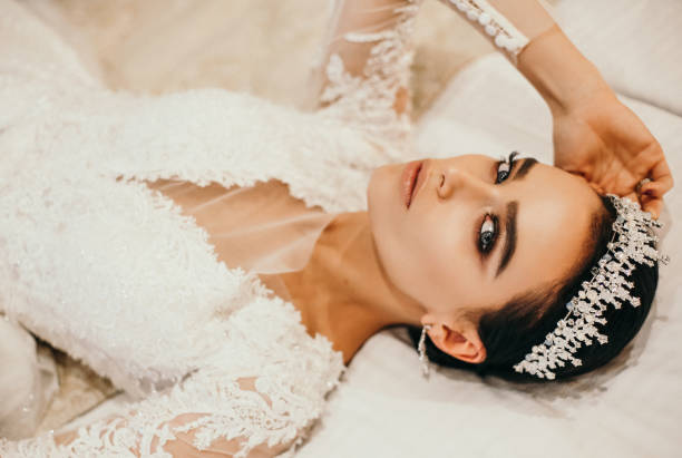 fashion photo of beautiful bride with dark hair in luxurious wedding dress fashion photo of beautiful sensual bride with dark hair in luxurious wedding dress and accessories posing in elegant interior of hotel hairstyle bride jewelry women stock pictures, royalty-free photos & images