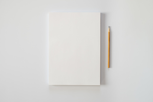 Una pila de hojas de papel en blanco y un lápiz sobre un fondo blanco. Crisis creativa o el comienzo de una nueva novela. photo