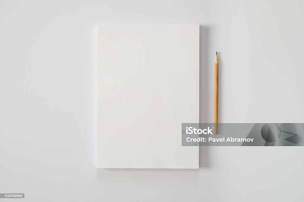 A stack of blank sheets of paper and a pencil on a white background. Creative crisis or the beginning of a new novel. Paper Stock Photo