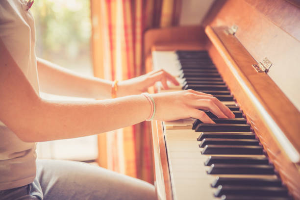 Girl is playing piano at home, high angle view, blurry background.