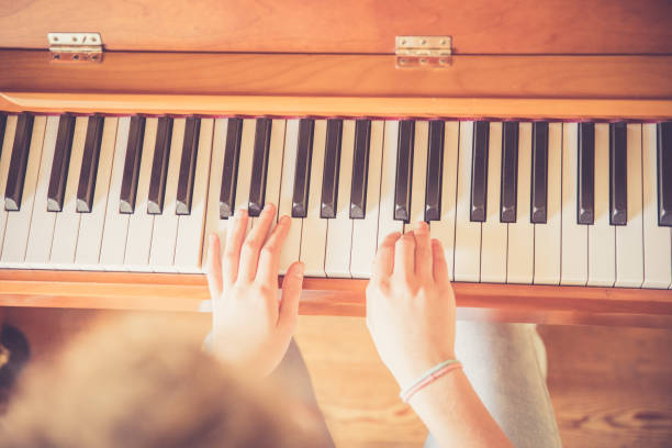 istock Girl is playing piano at home, high angle view, blurry background. 1133123526