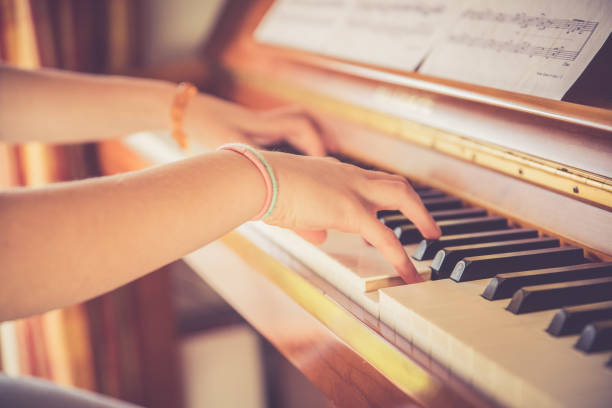 Girl is playing piano at home, high angle view, blurry background. stock photo