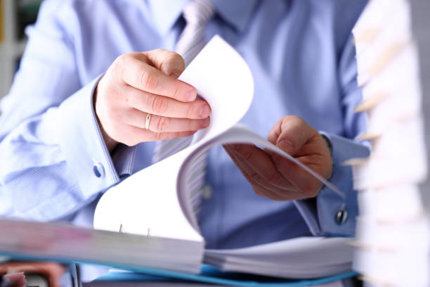 istock Clerk arm bend over pages in pile of documents closeup 1133125592