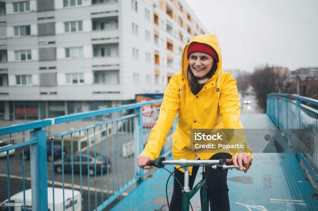 Chica en el impermeable amarillo montando bicicleta - Foto de stock de Andar en bicicleta libre de derechos