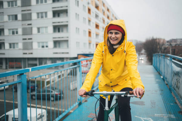 istock Girl in yellow raincoat riding bicycle 1133126001