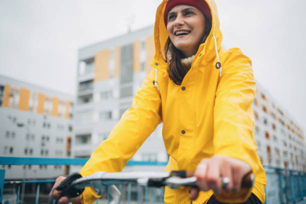 istock Girl in yellow raincoat riding bicycle 1133126018