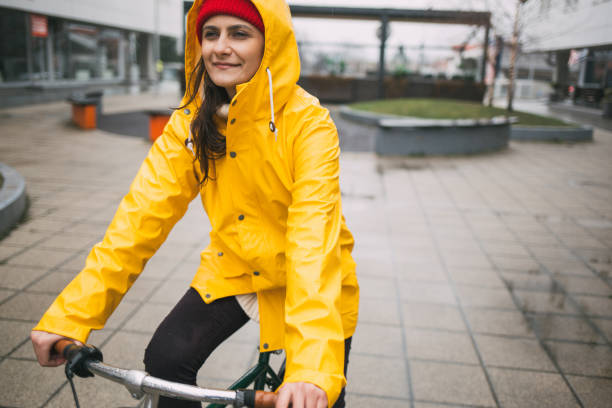 istock Girl in yellow raincoat riding bicycle 1133126129