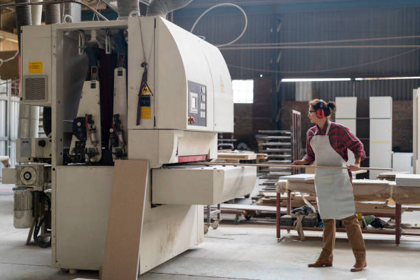 istock Mid adult craftswoman inserting wood in machine 1133142349