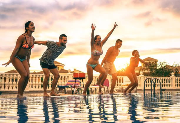 group of happy friends jumping in the pool at sunset - young people having fun making party in exclusive resort tropical in vacation - concept of friendship, holidays and youth lifestyle - life events laughing women latin american and hispanic ethnicity imagens e fotografias de stock