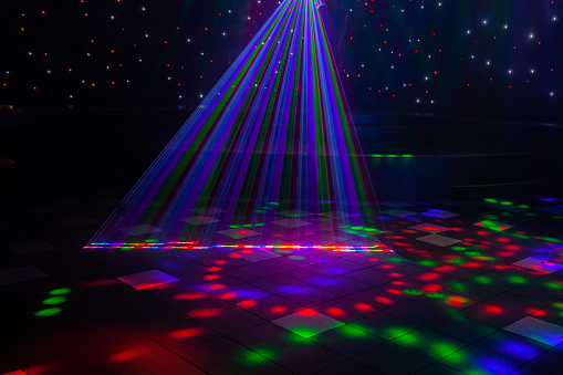 Night club laser lights making patterns on the dance floor in Australia with a stage setting in the background. Inspiration for Mardi Gras or nightlcub promotions.