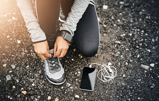 Closeup shot of a sporty woman tying her shoelaces while exercising outdoors
