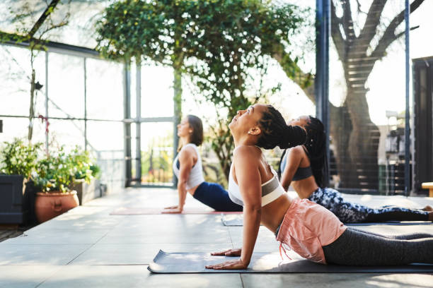 femme faisant vers le haut faisant face à la pose de crabot avec des amis - yoga class caucasian young adult group of people photos et images de collection