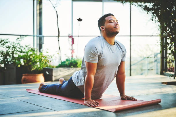 Young man practicing Upward Facing Dog Pose Mid adult man practicing Upward Facing Dog Pose. Handsome fit male is doing yoga on exercise mat. He is in sportswear. self improvement stock pictures, royalty-free photos & images