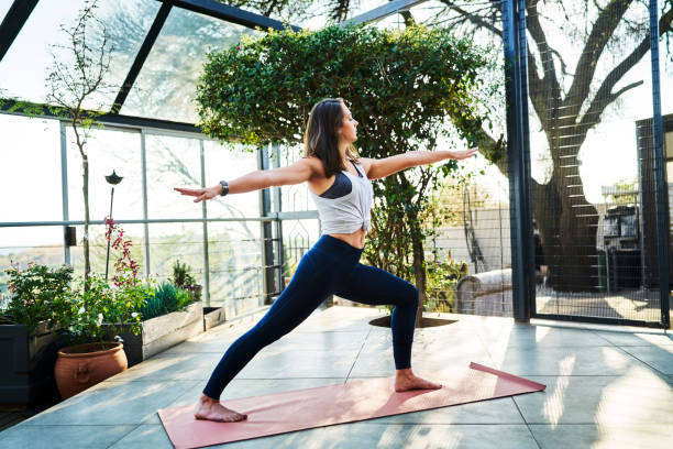 istock Young woman practicing Warrior Pose on yoga mat 1133155800