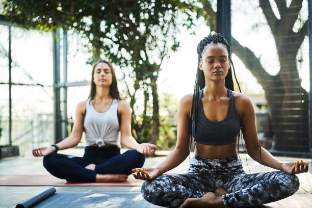 Young woman practicing lotus position with friend