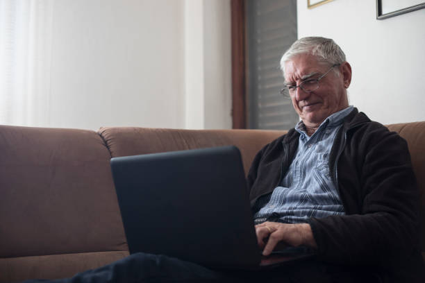 istock Smiling Senior Man Using Laptop While Relaxing in Living Room 1133157428