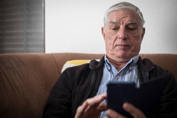 istock Surprised Senior Man Using Mobile Phone and Sitting on Sofa 1133157437