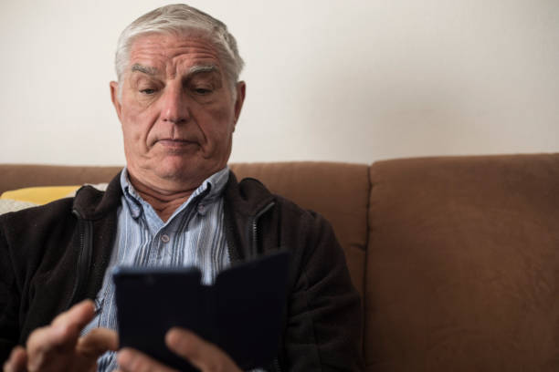 istock Surprised Senior Man Using Mobile Phone and Sitting on Sofa 1133157446
