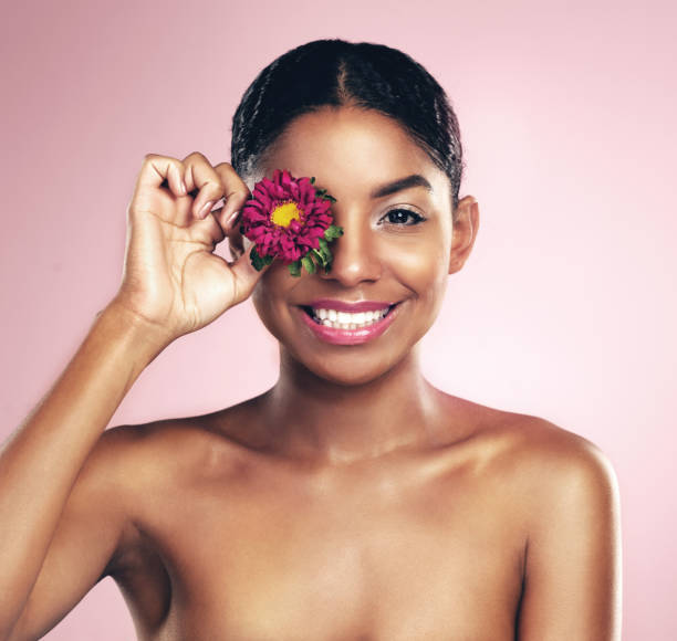 Shot of a beautiful young woman holding up a flower over her eye