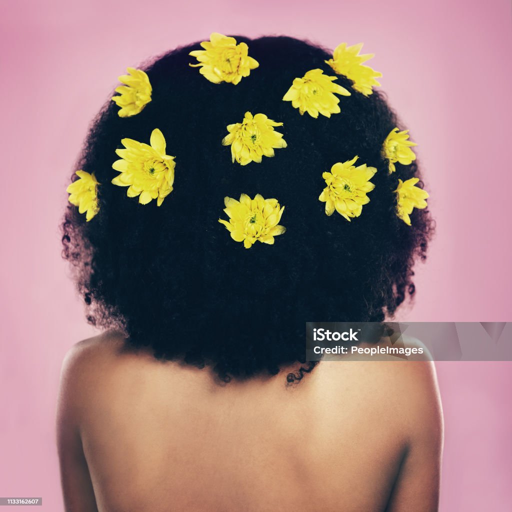 As natural as it gets Rearview shot of a woman standing with flowers in her hair Rear View Stock Photo