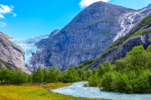 Briksdal or Briksdalsbreen glacier in Olden, Norway with green mountains, river and waterfall