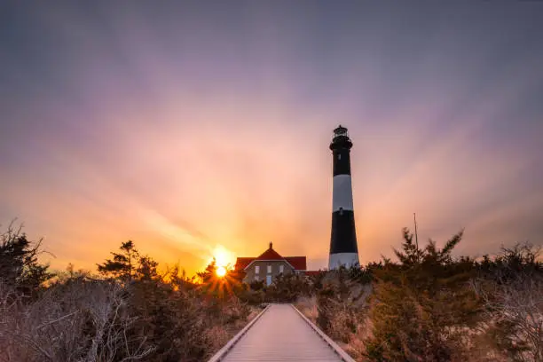 Photo of Boardwalk path leading to lighthouse at sunset.