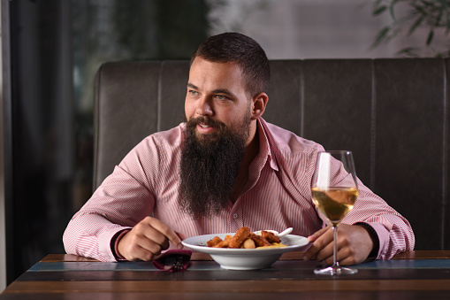 A single man sitting in a restaurant with wine
