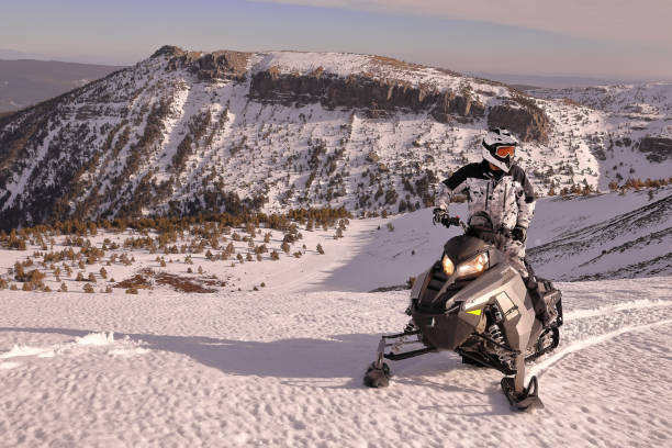 冬の雪の山の上にスノーモービルを走らせるライダー - snowmobiling snow winter mountain ストックフォトと画像